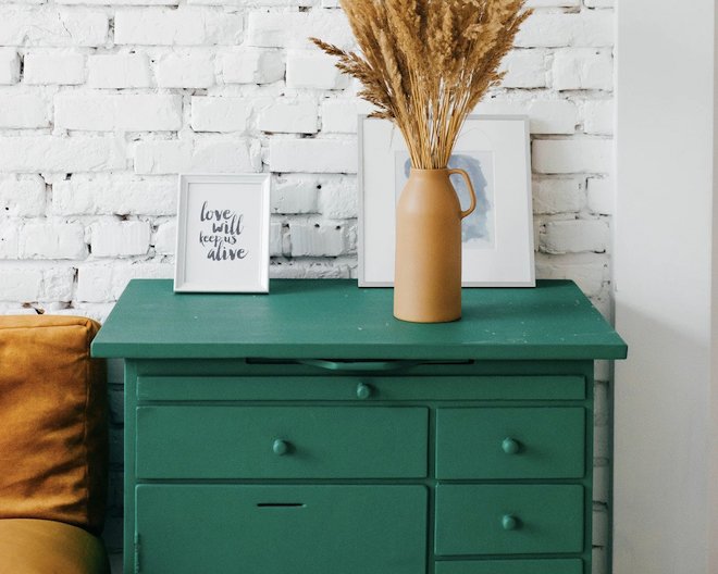 A blue drawer with a vase and a couple of photographs on top of it.